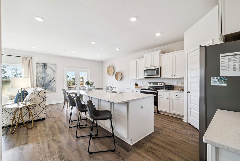 Your bright open kitchen flows seamlessly into the dining space, featuring crisp white cabinets and a spacious island perfect for morning coffee chats.