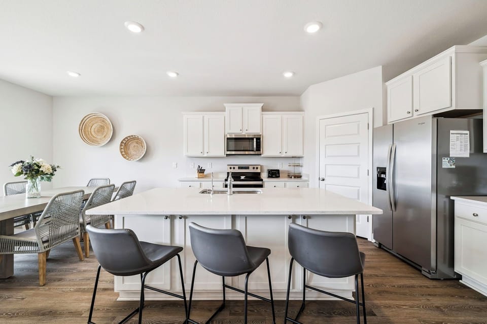 Your bright, modern kitchen features white cabinets, stainless steel appliances, and a spacious island with seating for casual meals.