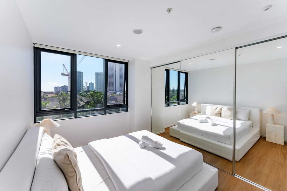 Modern bedroom featuring floor-to-ceiling mirrored closets and a stunning view