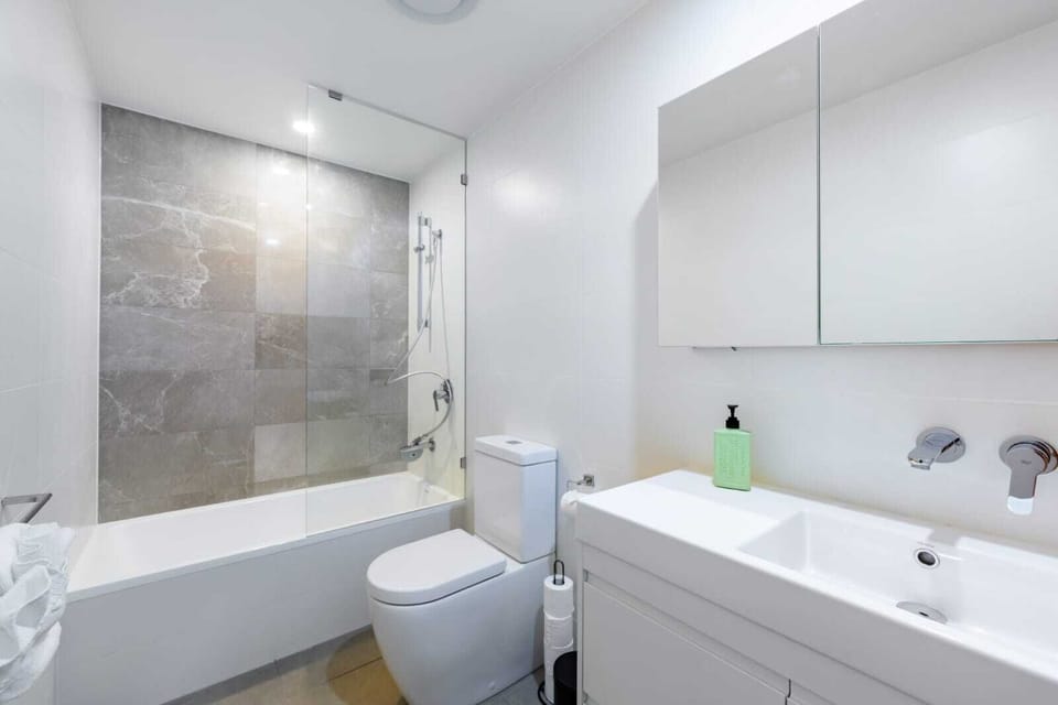 Sleek modern bathroom with bathtub, shower & vanity storage