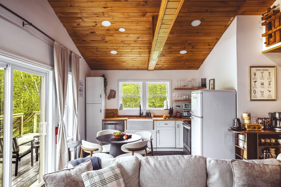 Open-concept living space at Inkwood Reserve — vaulted wood ceilings, cozy seating and a full kitchen with forest views in this Livingston Manor, NY Catskills cabin