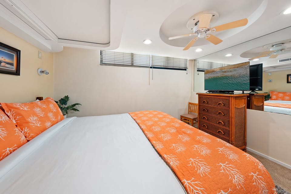 Bedroom includes a TV, dresser, and neatly made king bed.