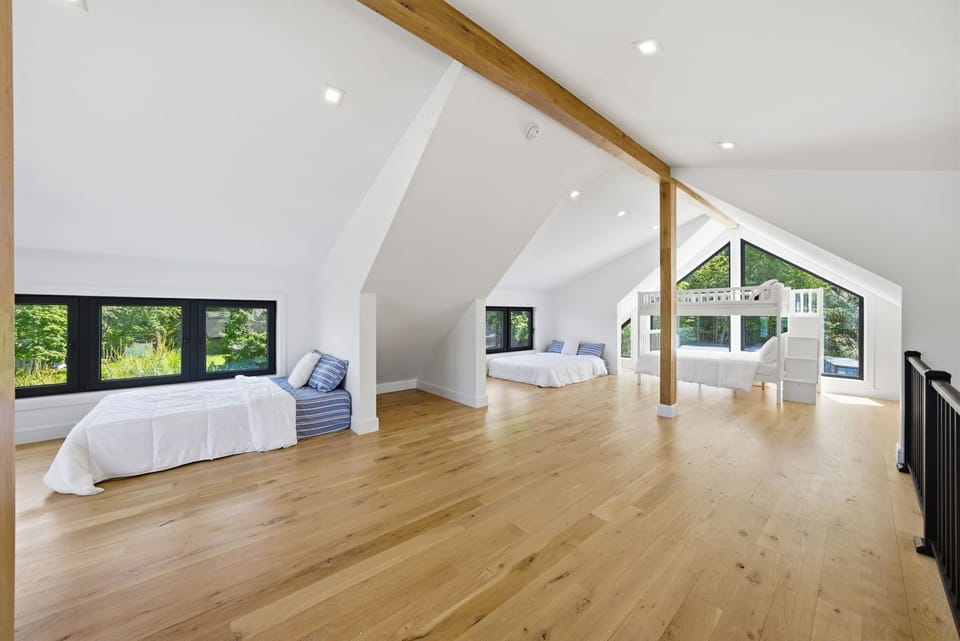 Large loft gathering and sleeping area with vaulted ceilings and natural light.