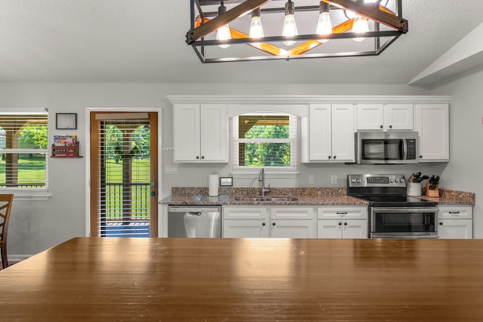 Fully stocked kitchen with updated stainless steel appliances.