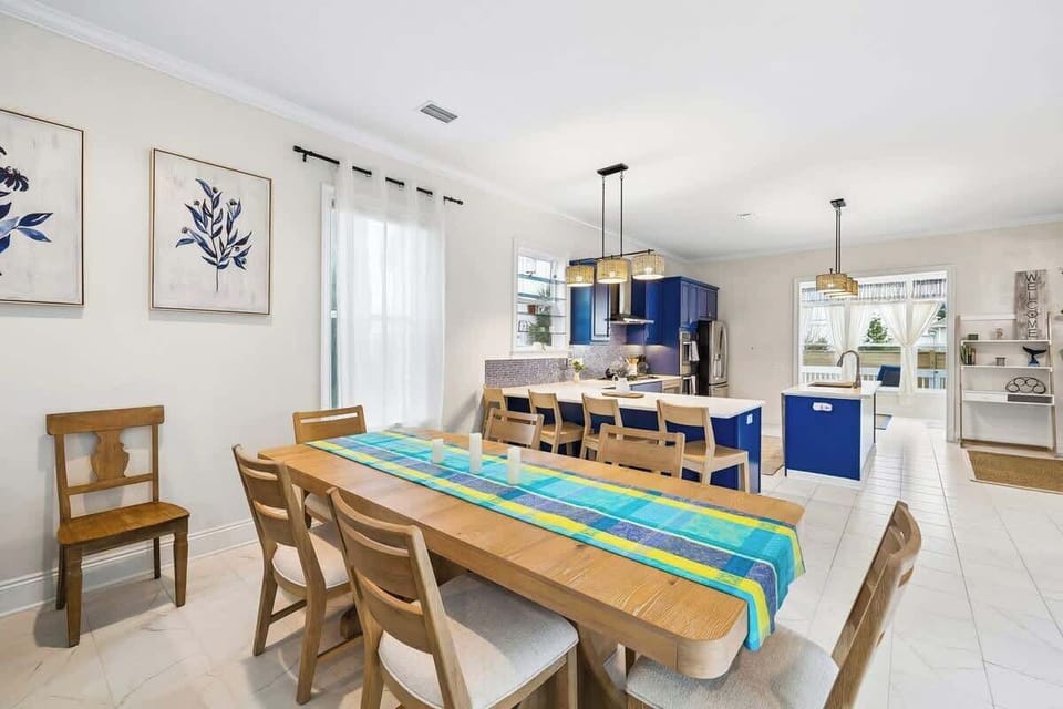 Coastal Dining & Kitchen Space

A seamless blend of dining and culinary spaces, featuring a warm wood dining table dressed with a colorful runner. The open-concept design flows into the vibrant blue kitchen, creating an inviting layout ideal for ente