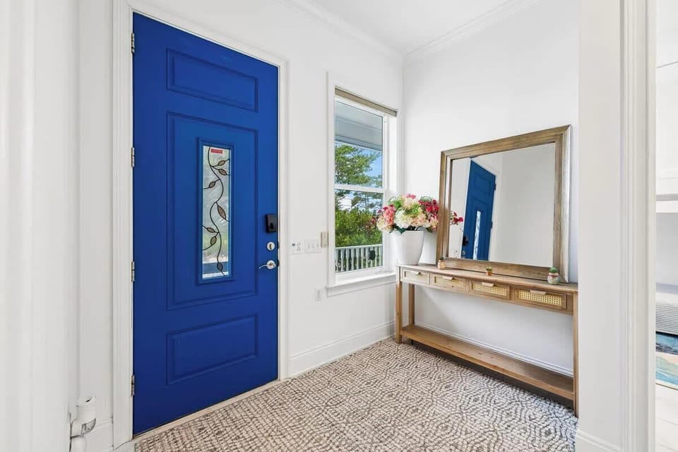 Vibrant Coastal Entryway

A welcoming entryway defined by a striking, bold blue front door with decorative stained glass. A wood console table, large matching mirror, and textured patterned rug create a bright, inviting first impression.