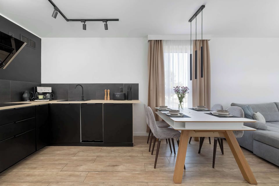 A modern kitchen and dining area in an open-plan layout. Dark cabinets contrast with the light interior.