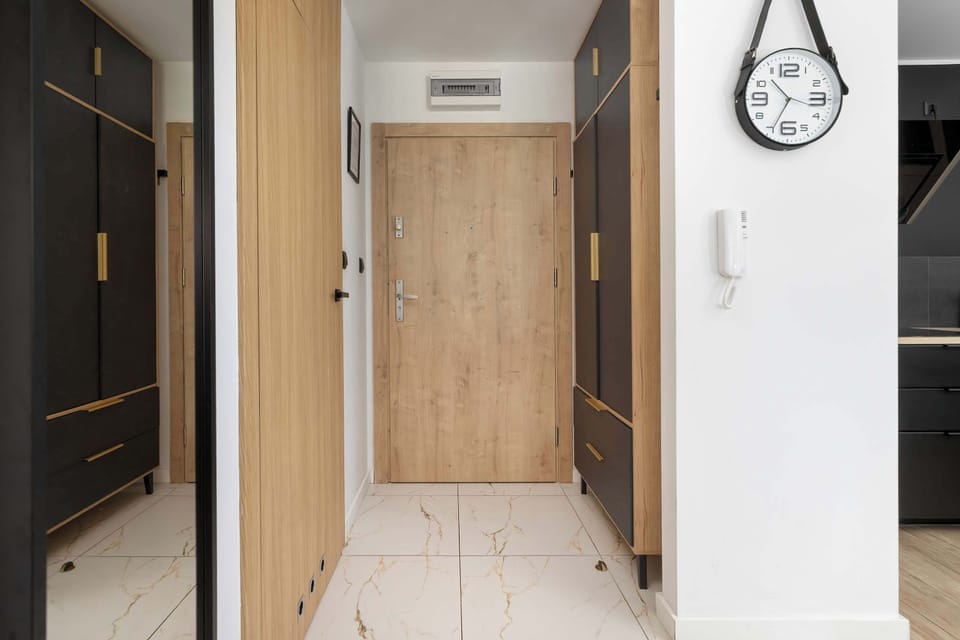 A hallway with light-colored flooring and wooden doors. The interior is modern and well maintained.