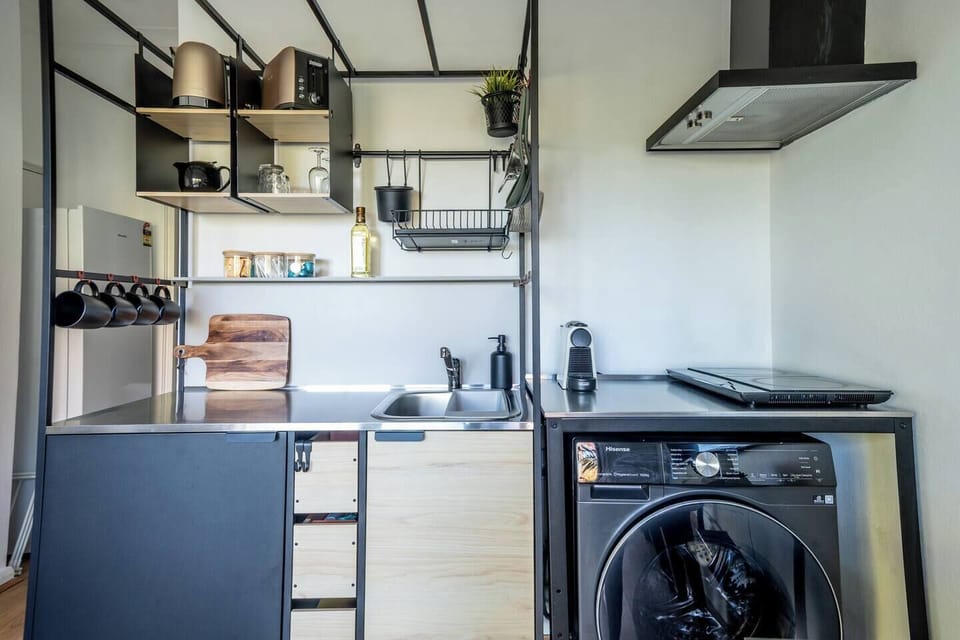 The compact kitchenette and laundry area combine everyday convenience with thoughtful essentials for extended stays, including a Nespresso machine, washing machine, and dining essentials.