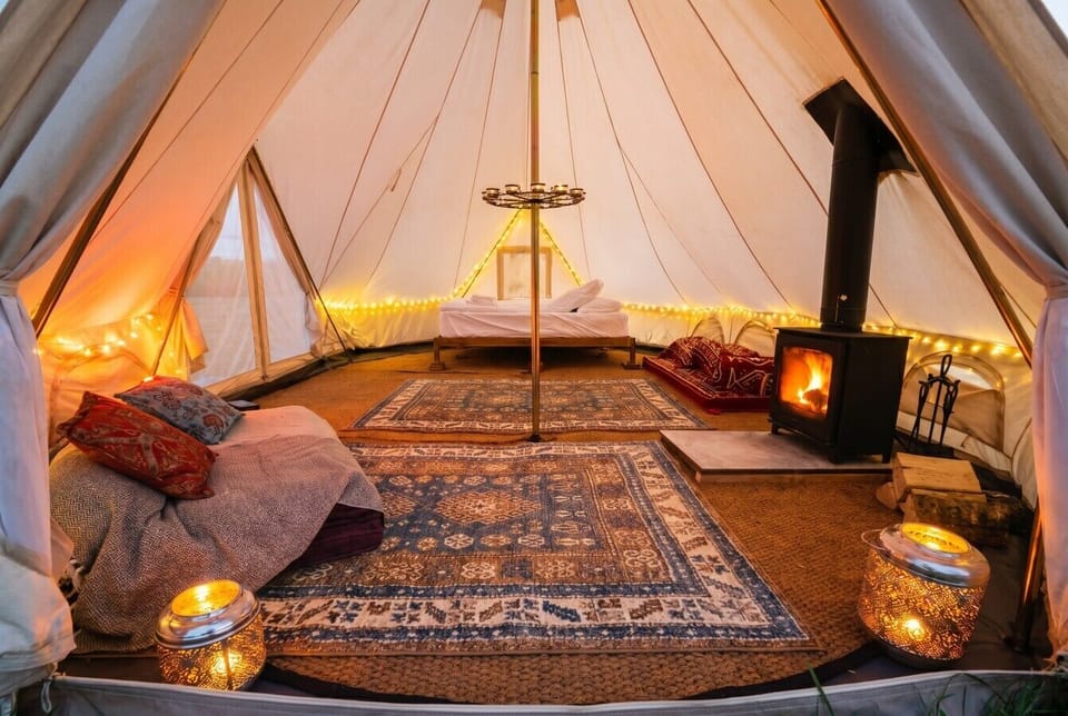 Snug interior with woodburner, layered rugs and lanterns aglow