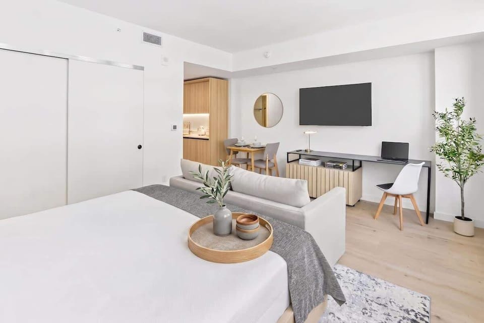 Bright open studio featuring a cozy sleeping area with comfortable linens, stylish furnishings, and a Smart TV for relaxing stays.