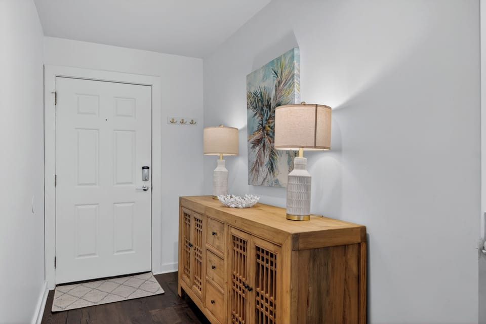 Step through the front door into a bright, welcoming entryway styled with coastal-inspired décor and warm wood accents that set the tone for your getaway.