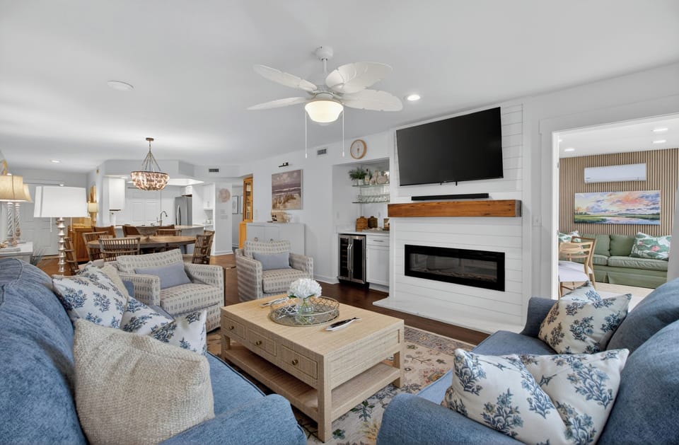 Unwind in your coastal-inspired living room, where cozy seating surrounds a modern fireplace, perfect for gathering after a day exploring nearby attractions.