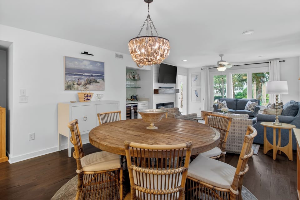 Gather around the elegant dining table under a stunning chandelier, with coastal-inspired décor and an open flow to your living space, perfect for memorable meals and conversation.