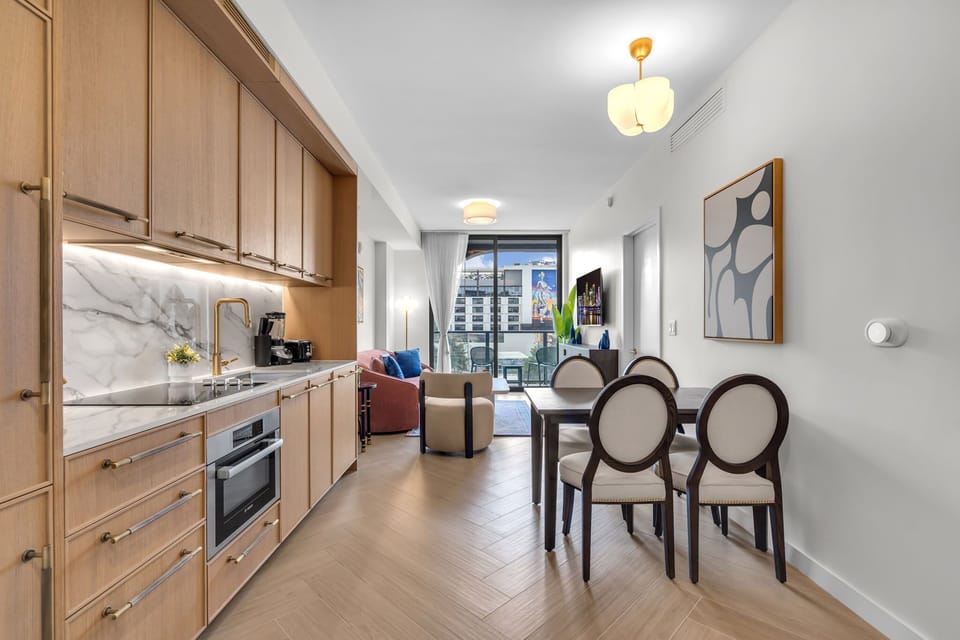 Open-concept kitchen and dining area with premium appliances, warm wood cabinetry and a stylish dining set — perfect for meals in