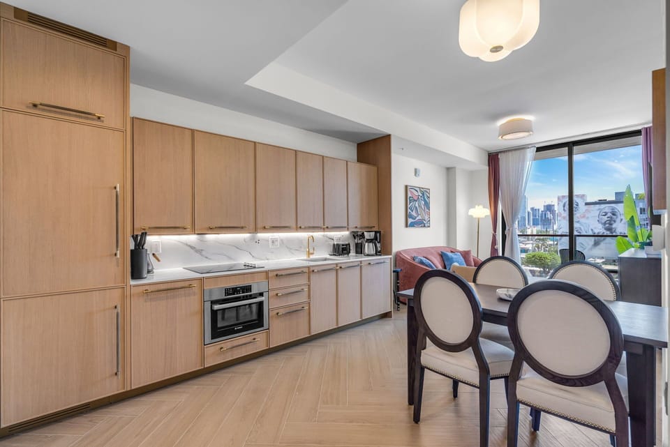 
Open-concept kitchen and dining area with premium appliances, warm wood cabinetry and a stylish dining set — perfect for meals in