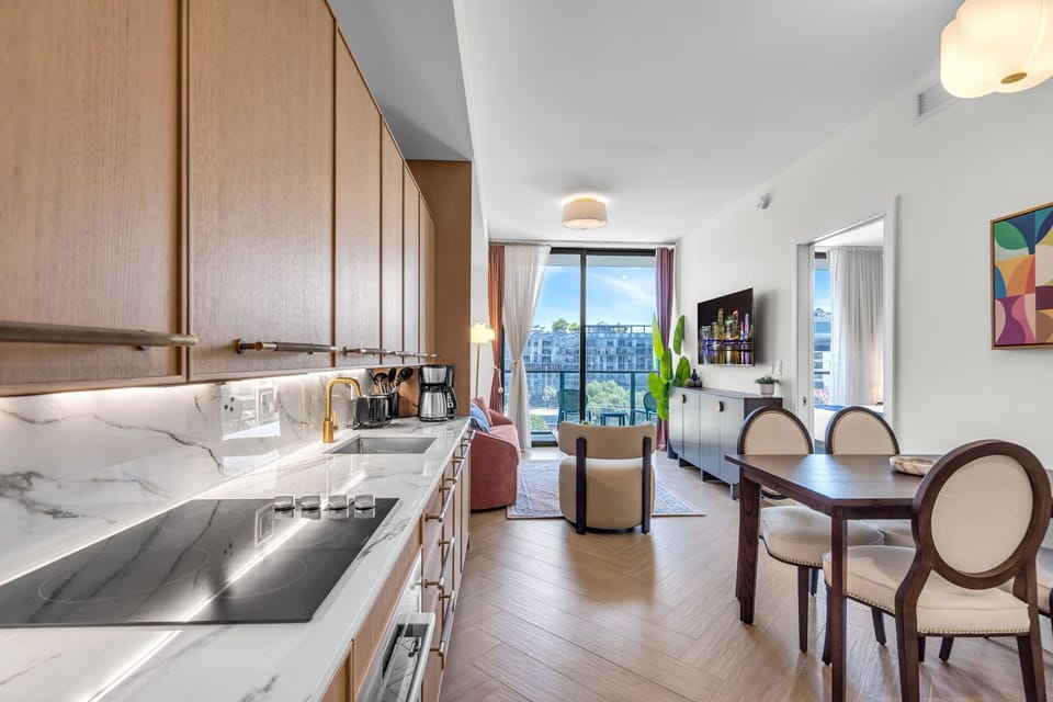 Elegant in-unit dining area with designer chairs, warm wood cabinetry and stylish pendant lighting — perfect for intimate meals at home