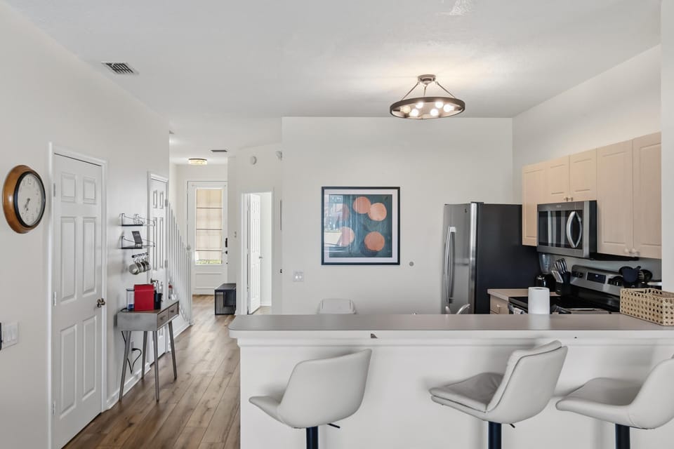 Kitchen features stainless steel appliances, light wood cabinets, and a breakfast bar with swivel stools.