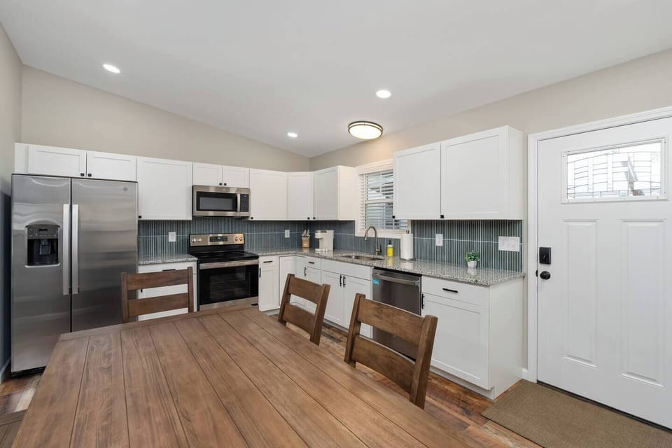 The kitchen includes matching GE stainless steel appliances, granite countertops, and a vertical stack KitKat backsplash.  There's plenty of space to prep a meal or set out food you've ordered.  A large Pottery Barn table makes room for a feast.