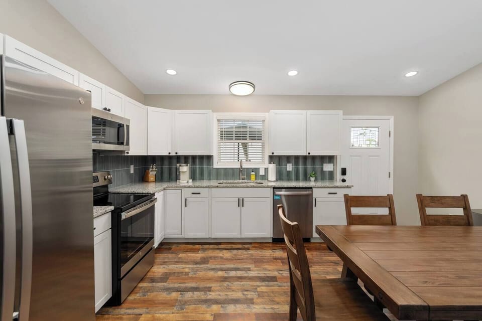 The kitchen includes matching GE stainless steel appliances, granite countertops, and a vertical stack KitKat backsplash.  There's plenty of space to prep a meal or set out food you've ordered.  A large Pottery Barn table makes room for a feast.