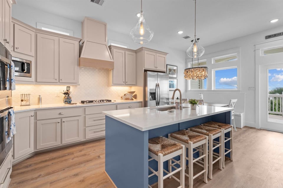 Gourmet kitchen with oversized island, bar seating, pendant lighting and stainless steel appliances.