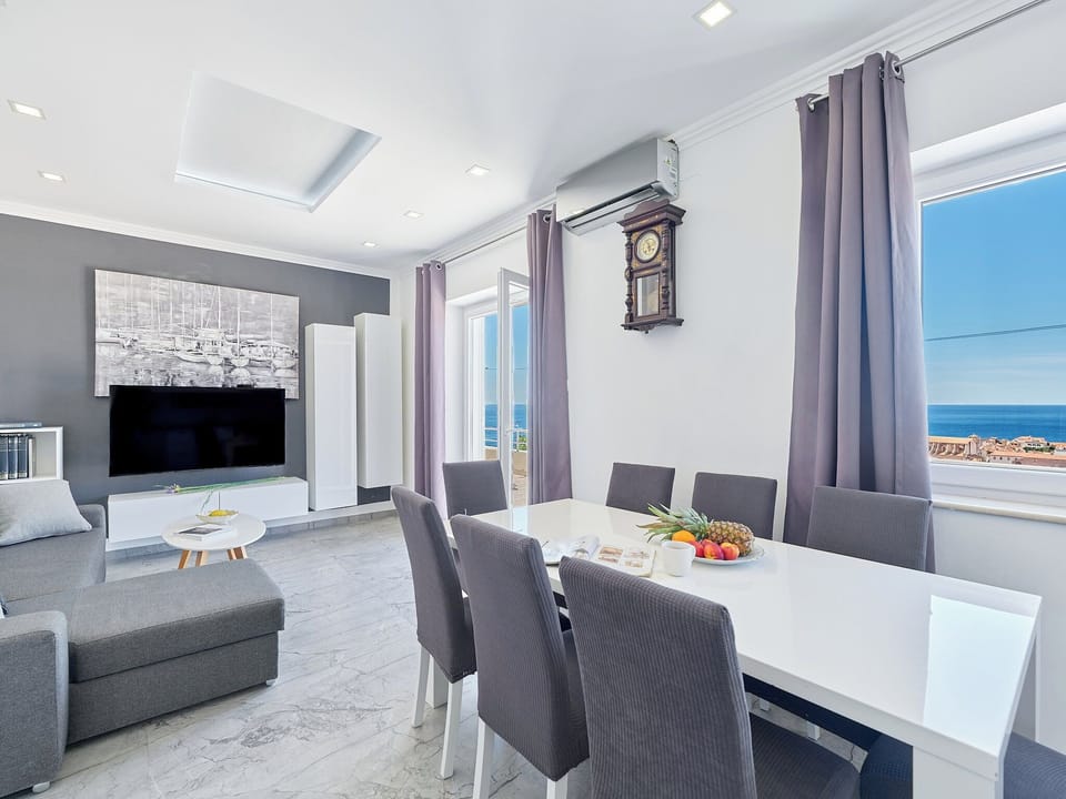 This bright, open-concept living area features modern decor and elegant dining. Windows frame sparkling Adriatic views.