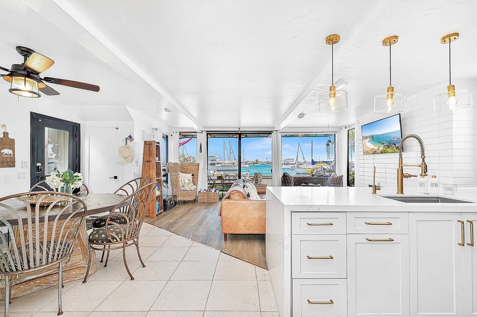 Bright bayfront living room with cozy seating and panoramic harbor views
                