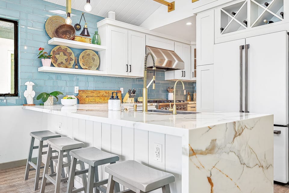 Open kitchen with a large island flowing into the bright coastal living area
                