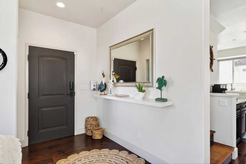A clean, welcoming entryway foyer featuring a built-in display shelf and sleek dark front door.