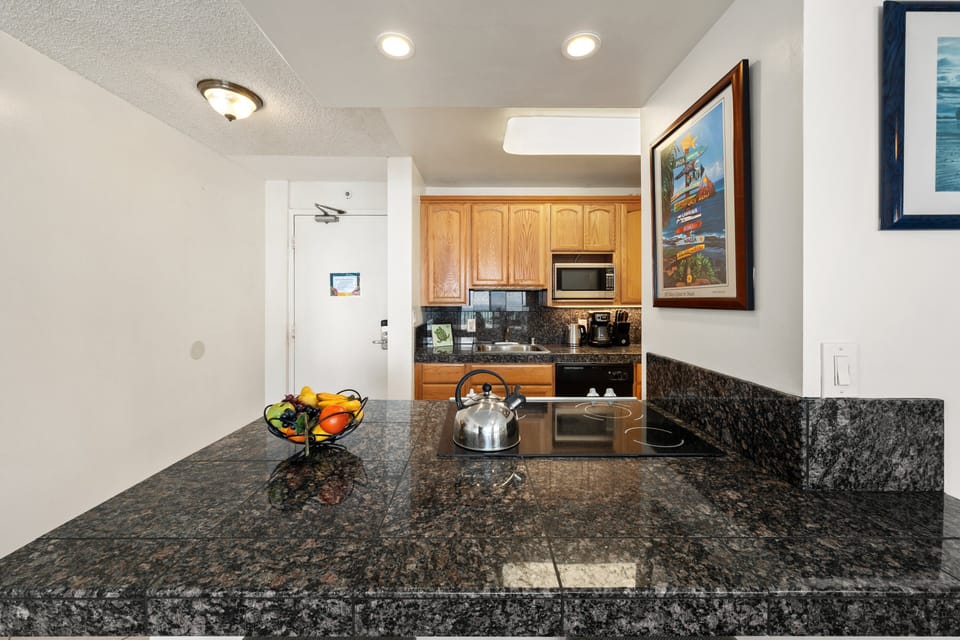 Granite breakfast bar with seating, flowing into a full kitchen.