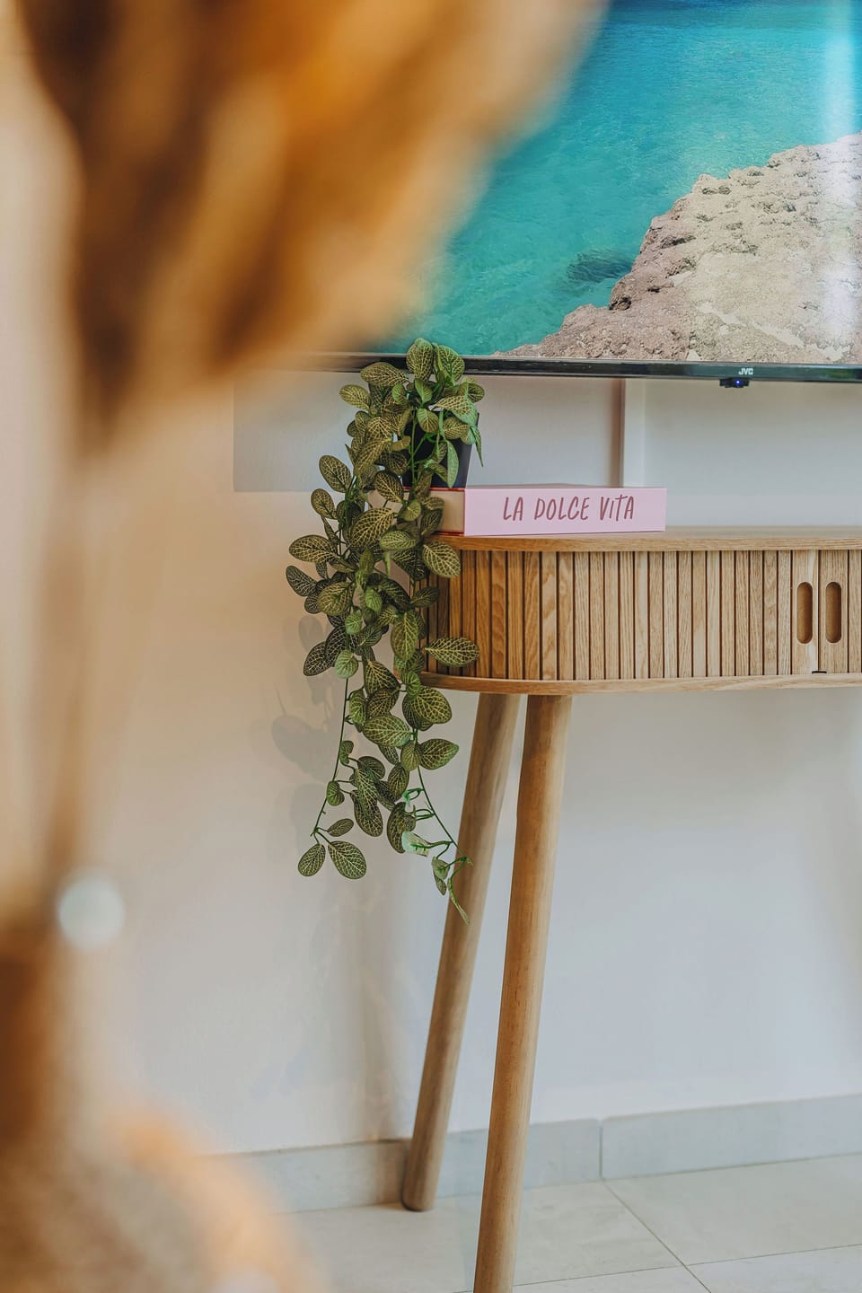 Cascading greenery and warm wood finishes bring softness and charm to the apartment’s modern interior details.