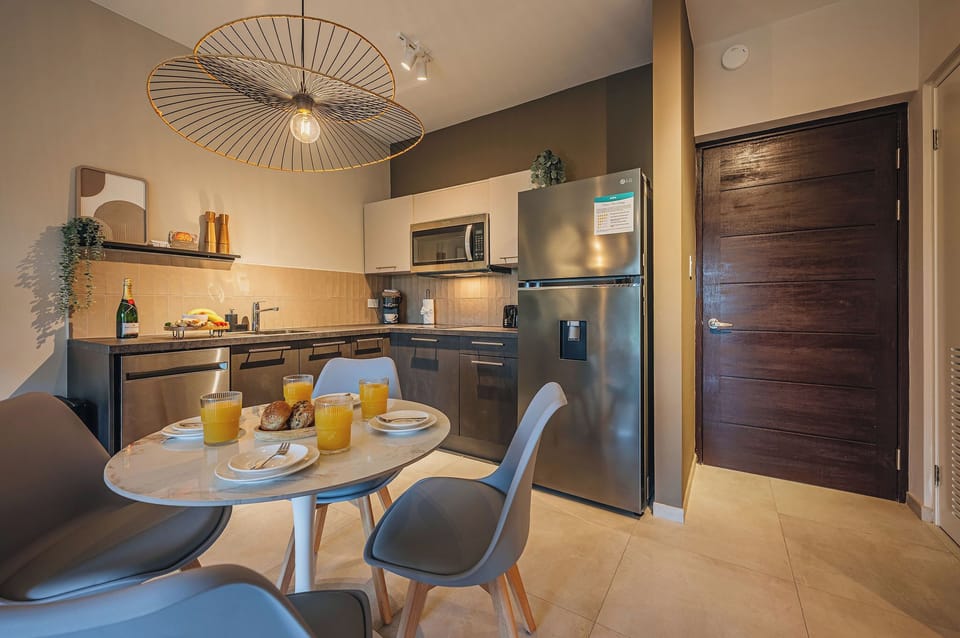 Sleek dark cabinetry and modern finishes create a polished kitchenette with a warm contemporary island feel.
