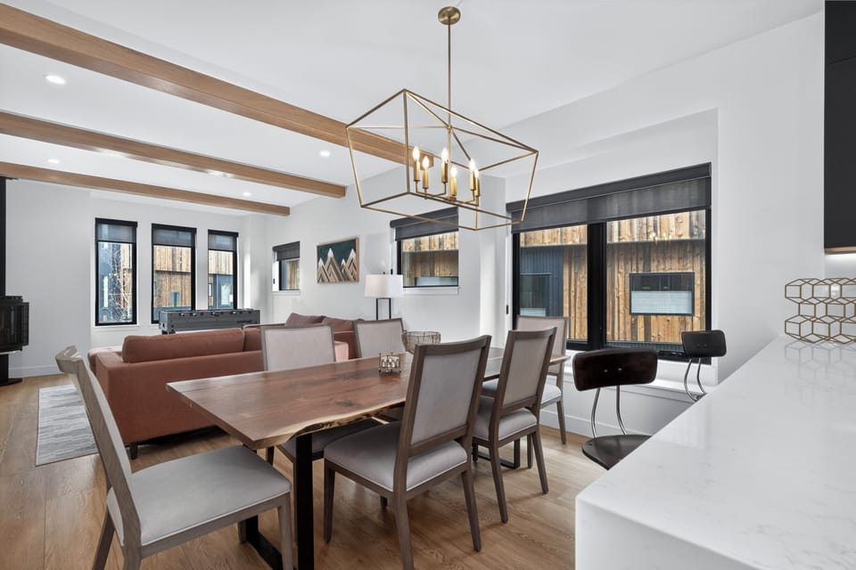 Gather around this stunning live-edge dining table under vaulted ceilings with exposed beams. Your bright, open living and dining area features modern mountain design and abundant natural light.