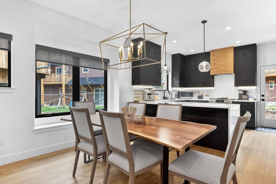 Picture yourself hosting dinners in this beautifully designed open-concept space. The sleek modern kitchen with black cabinetry and warm wood accents flows seamlessly into your cozy dining area.