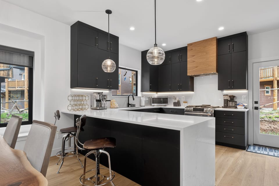 Your modern chef's kitchen features sleek black cabinetry, bright white quartz countertops, and a spacious island perfect for prepping meals or sharing stories over morning coffee.