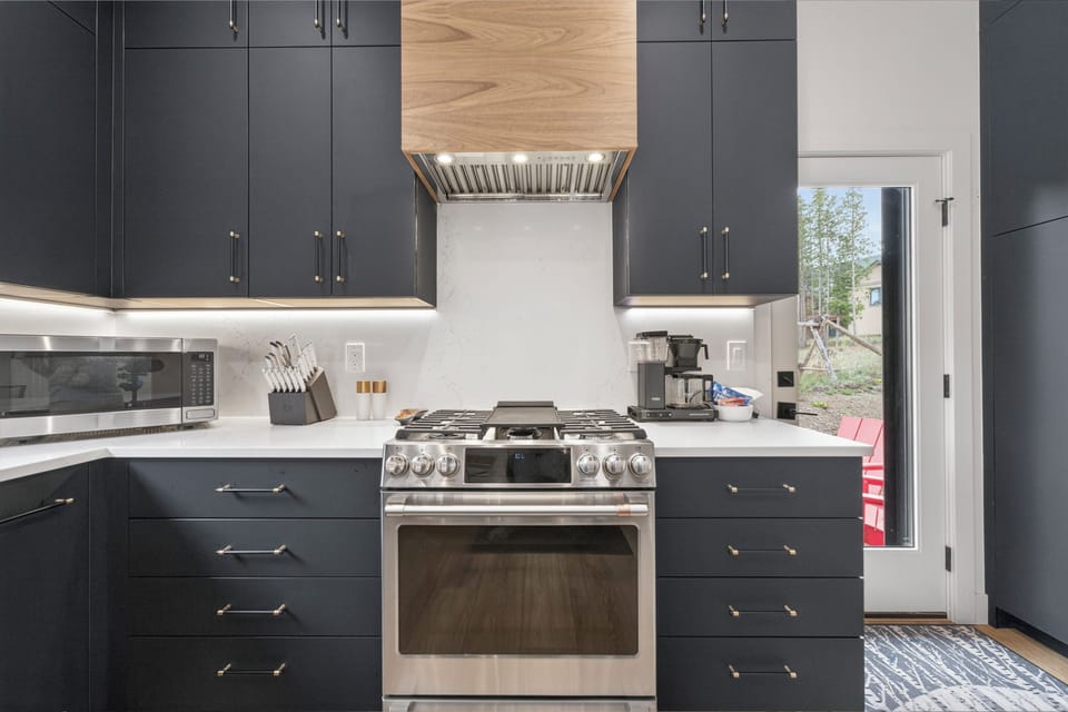 Your gourmet kitchen features sleek dark cabinetry, premium stainless appliances, and bright marble countertops—perfect for preparing memorable meals during your stay.