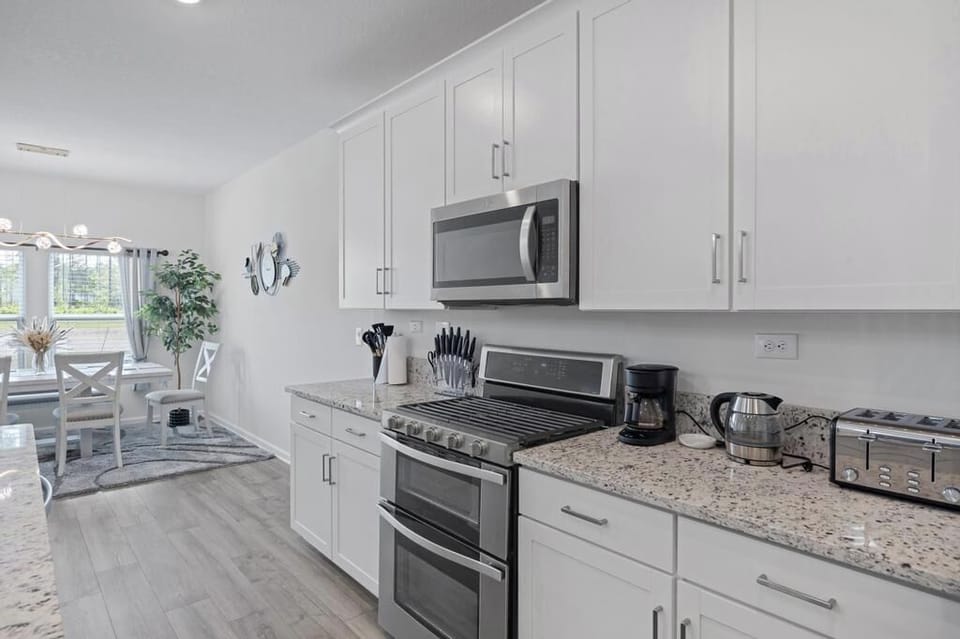 Modern kitchen w/ stainless appliances, white cabinetry & ample counter space.