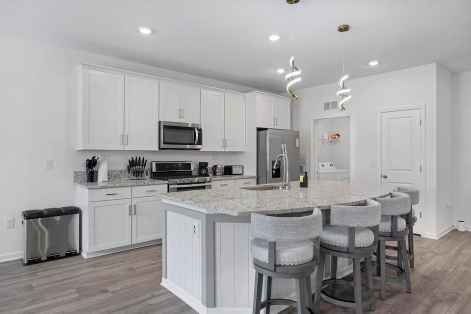 Sleek white kitchen w/ island seating & stainless appliances — great for cooking together.