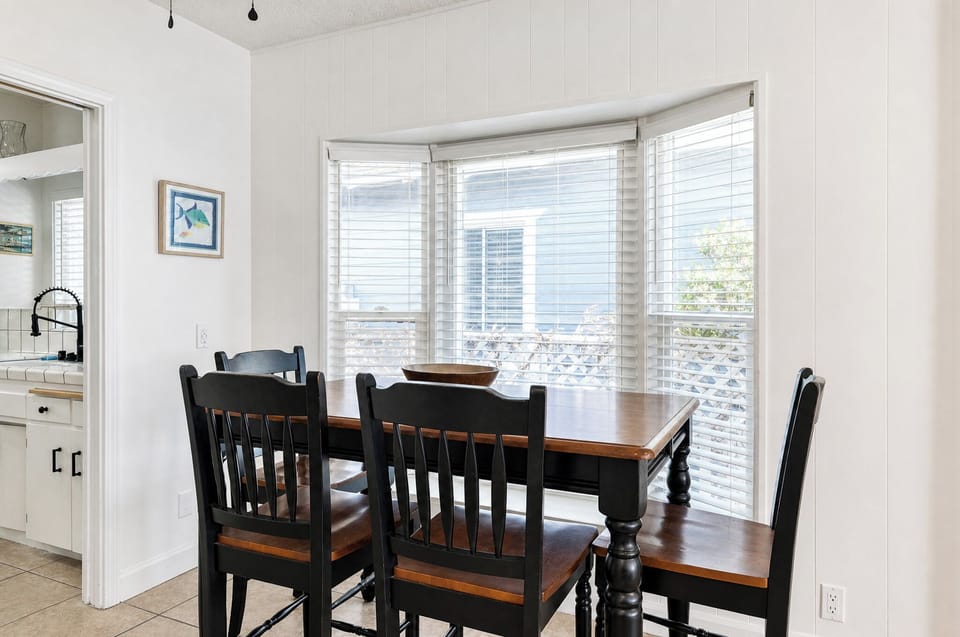 Gather around this inviting dining table, where warm wood tones and coastal touches create the perfect spot for your morning coffee or evening meals together.