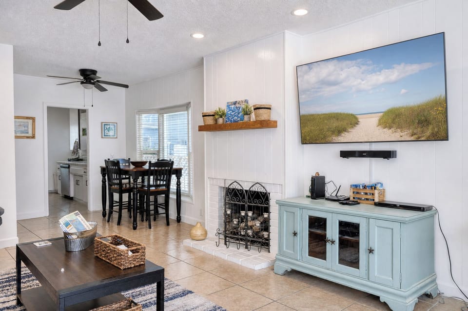 Relax in your bright open living space with coastal-inspired décor, ceiling fans for comfort, and a beautiful beach path artwork that captures the tranquil vacation vibe.