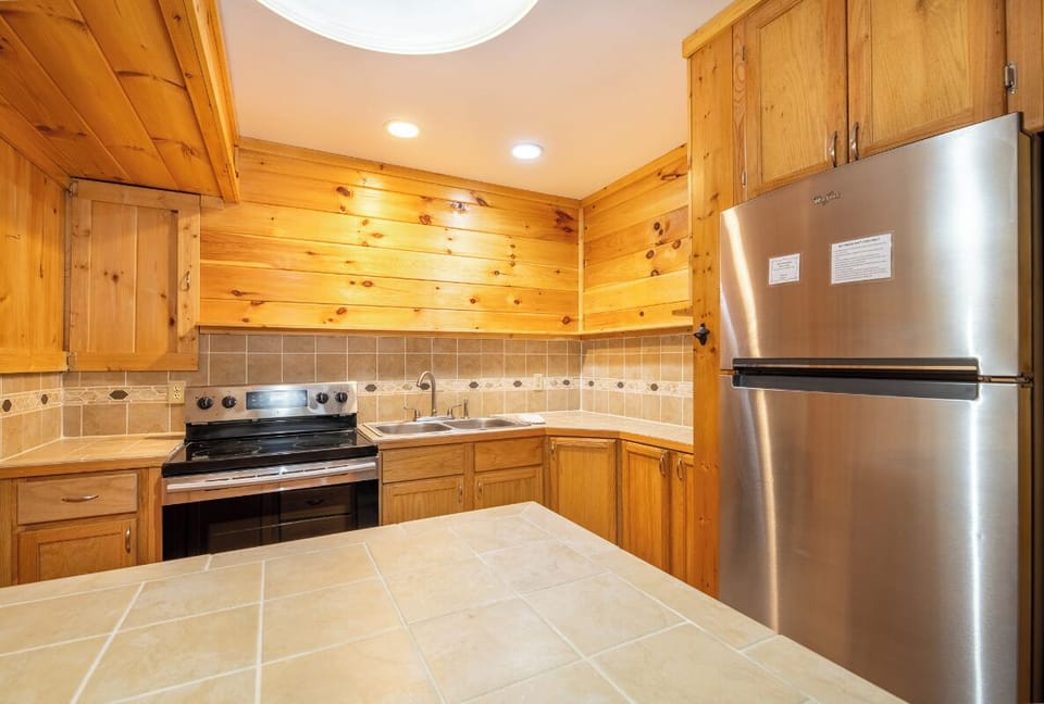 This kitchen features warm cabinetry, modern stainless steel appliances, and tile backsplash—your home base for preparing meals and gathering with loved ones.