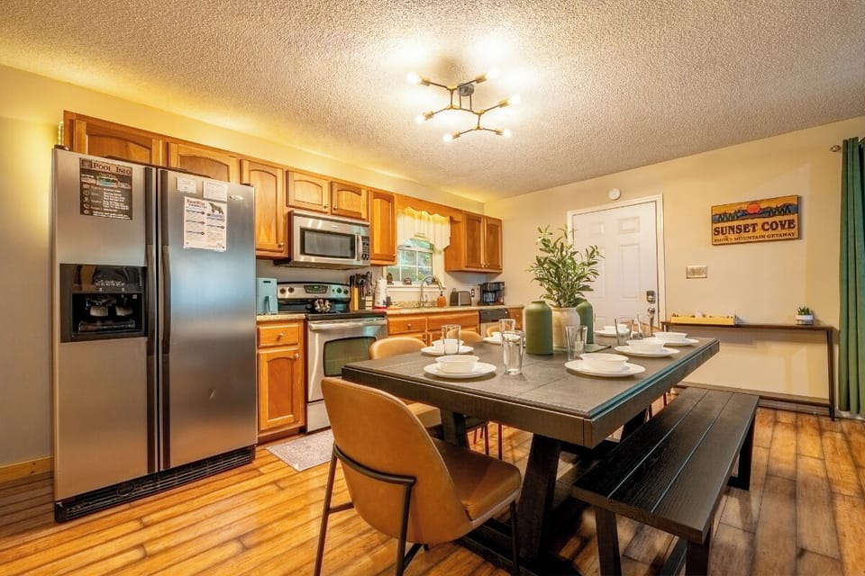 Gather around this inviting dining table in your fully equipped kitchen, ready for shared meals and conversation. The stainless appliances and warm wood floors create a comfortable home base for your stay.