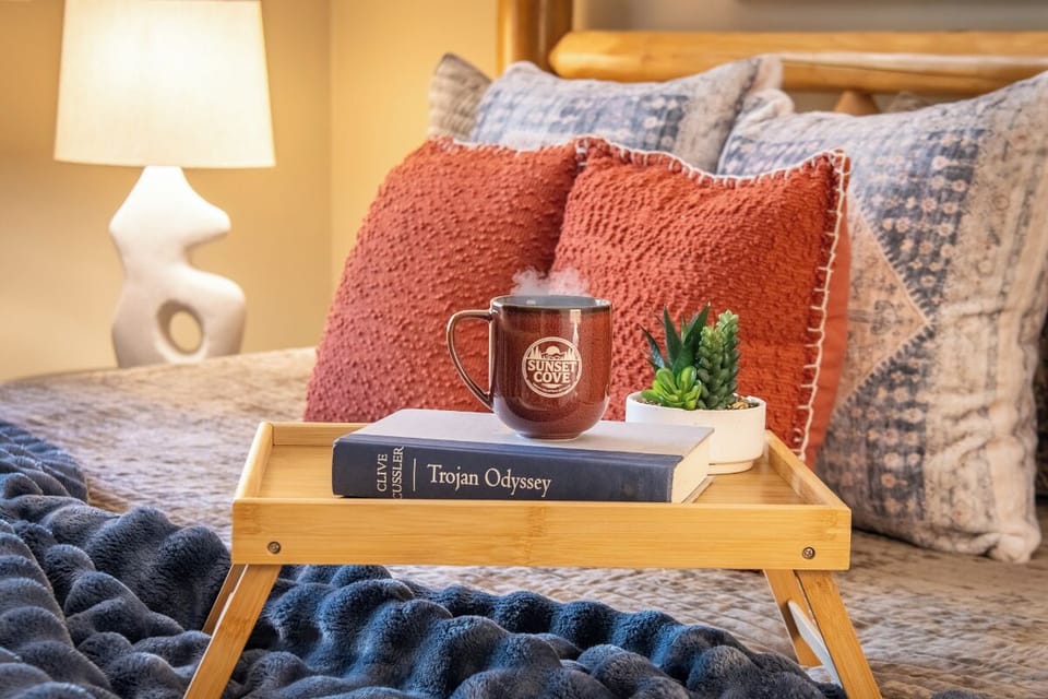 Sink into plush bedding and enjoy your morning coffee on a rustic lap tray, with soft throw pillows and warm lighting creating the perfect cozy retreat.