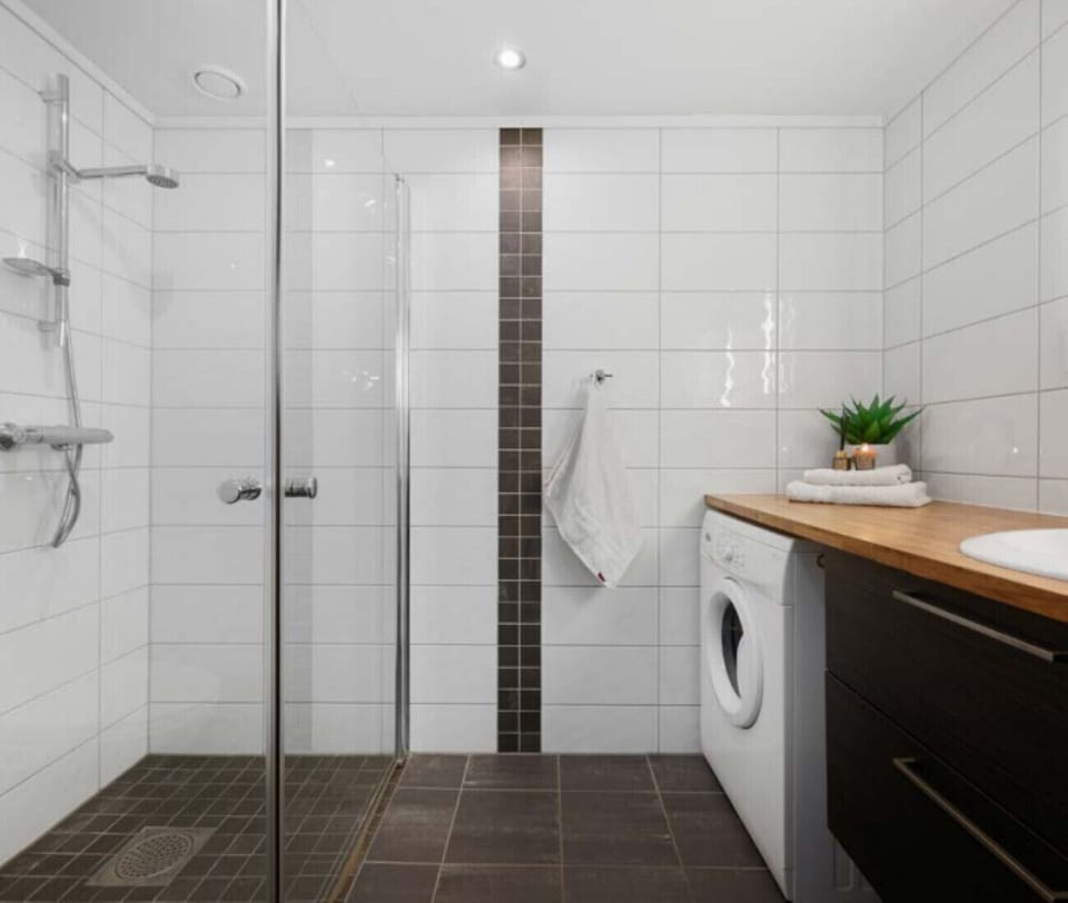 The bathroom has a shower and a washing machine
