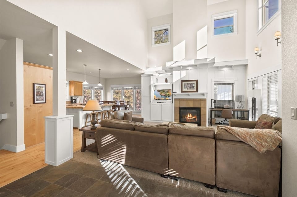 Living room with sectional sofa, fireplace, large smart TV, a work space, plus plenty of natural light.