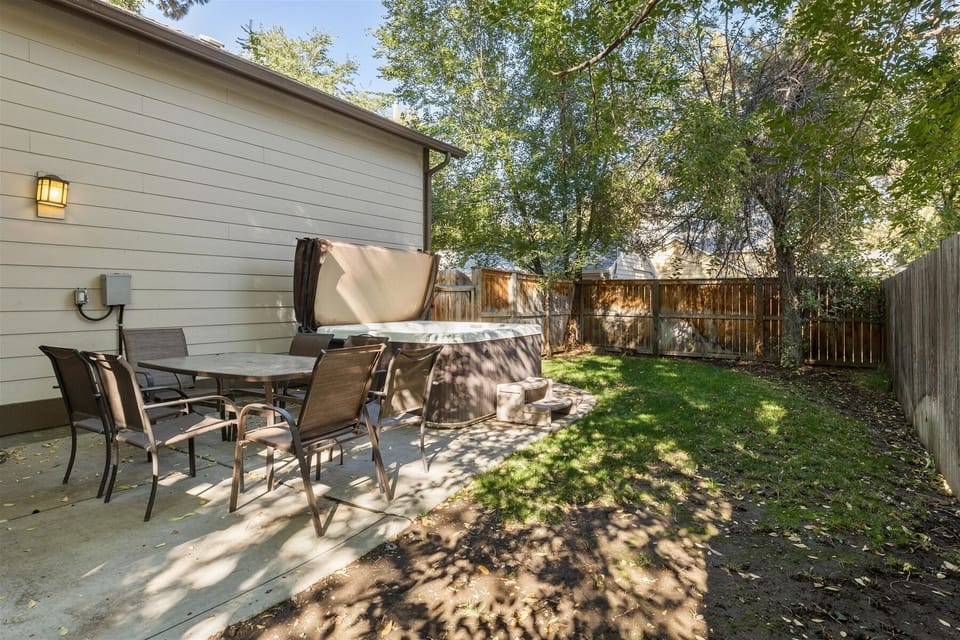Fenced backyard with outdoor dining area and hot tub.