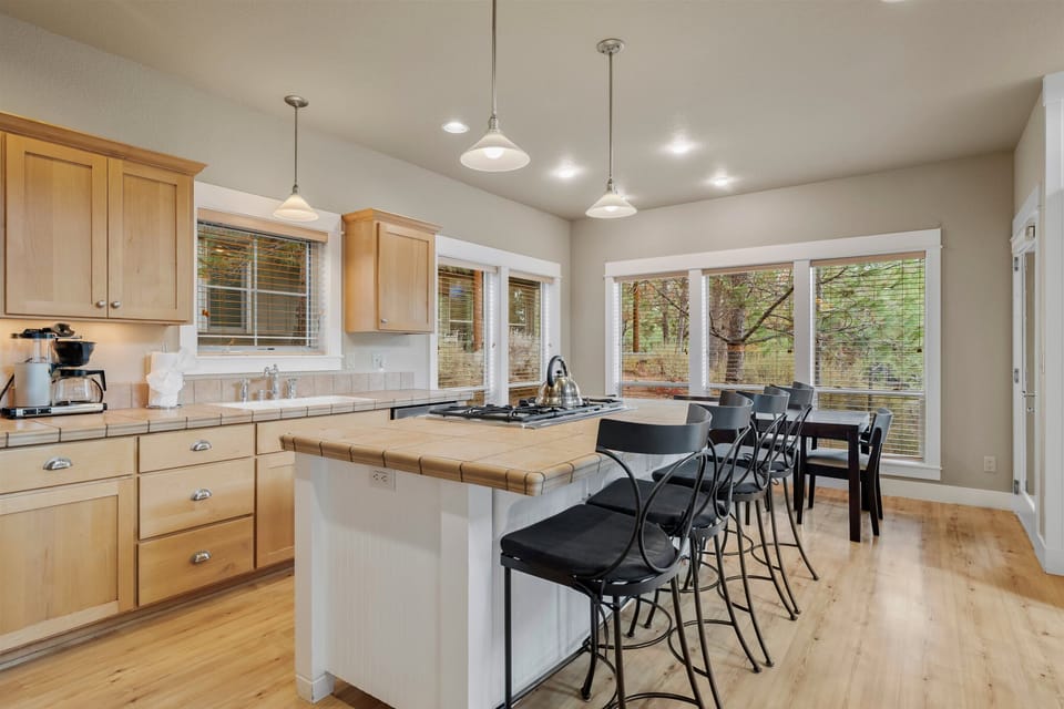 Bright kitchen with island, pendant lighting, wood cabinetry, and tree views.