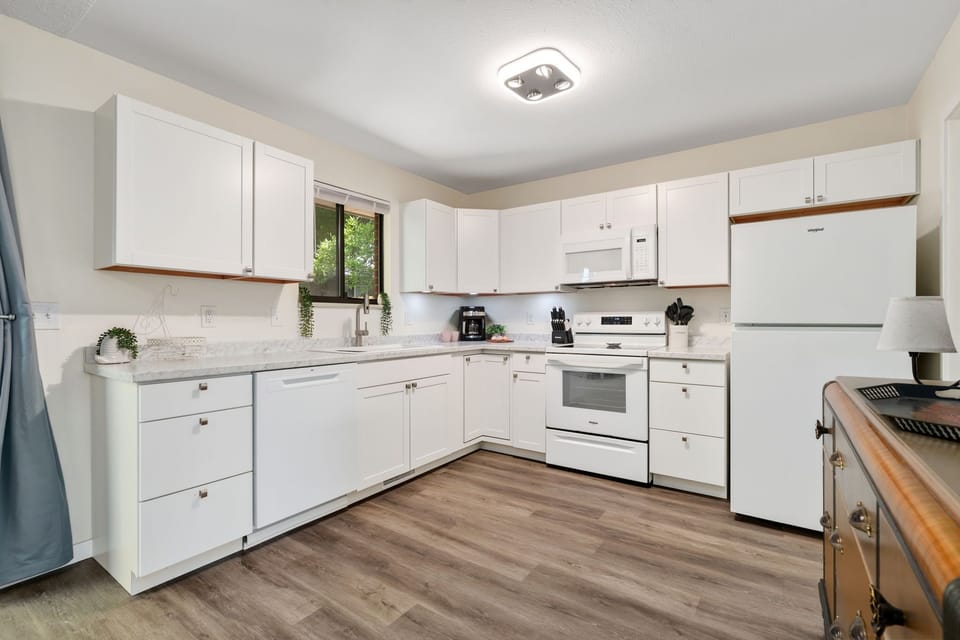 Bright, spacious kitchen with crisp white cabinetry and ample counter space for your favorite home-cooked meals. Natural light streams through the garden window above the sink.