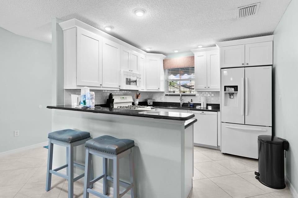 Prepare your favorite meals in this fully-equipped kitchen featuring modern appliances, stylish white cabinetry, sleek countertops, and a breakfast bar for casual dining.