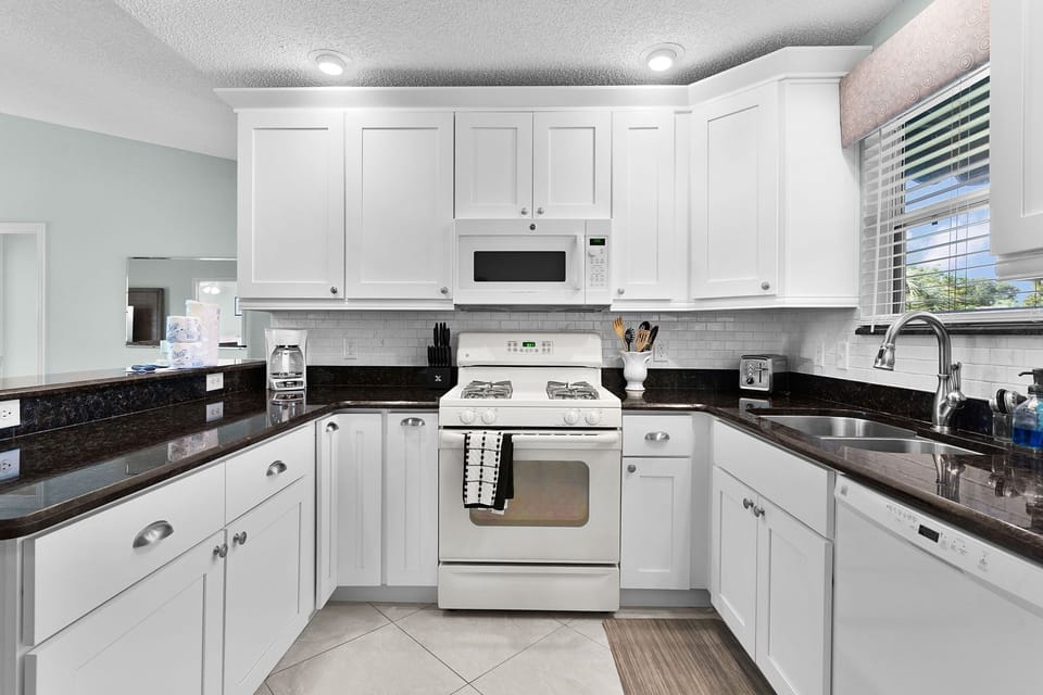 You'll love whipping up meals in this bright, fully equipped kitchen with sleek granite counters, white cabinetry, and modern appliances—everything you need for cooking at home.